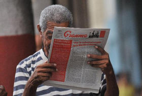 Un cubano lee el periódico del Partido Comunista Granma que informa sobre una nueva ley de inmigración, en La Habana el 16 de octubre de 2012