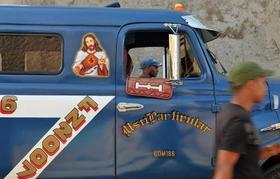 Un hombre camina junto a un vehículo particular, decorado con la imagen de Jesús, el 9 de diciembre de 2008, en la ciudad de Santiago de Cuba. (EFE)