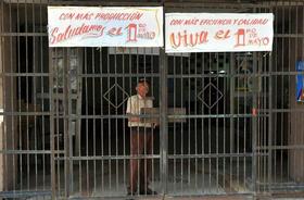 Un cubano permanece en el interior de una fábrica el jueves 29 de abril de 2010, con carteles alusivos al desfile del Primero de Mayo en la Plaza en la Revolución en La Habana