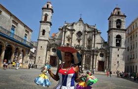 Una mujer vestida con la bandera cubana vende muñecas en la Plaza de la Catedral de La Habana