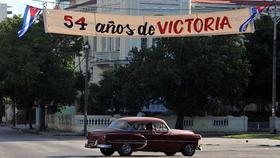 Varias personas caminan junto a un cartel de contenido revolucionario, el sábado 24 de diciembre de 2011, en La Habana