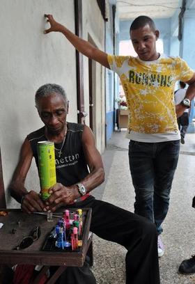 Un hombre llena una fosforera en su negocio por cuenta propia en La Habana. EFE