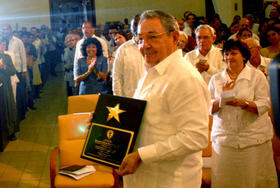 El presidente cubano, Raúl Castro (c), muestra la Placa Conmemorativa que le fue otorgada en un acto por el setenta aniversario del Consejo Nacional de Iglesias