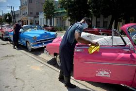 Limpieza de autos antiguos propiedad de una empresa privada de taxis en La Habana