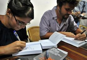 Elizabeth Mirabal (i) y Carlos Velazco (d) firman ejemplares de Sobre los pasos del cronista