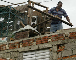 Inventando. Un hombre en el tejado de su casa. (AP) Inventando. Un hombre en el tejado de su casa. (AP)