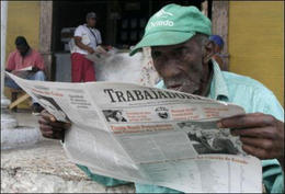 Un hombre lee un periódico en el que aparece la imagen de Raúl Castro Un hombre lee un periódico en el que aparece la imagen de Raúl Castro