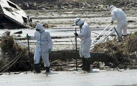 Policías protegidos de la raciación buscan víctimas del tsunami en Minamisoma en la prefectura de Fukushima (Japón)