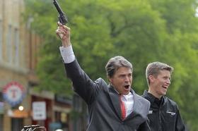 El gobernador de Texas, Rick Perry, dispara al aire durante un acto