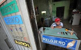 Un relojero a la espera de clientes en un pequeño taller privado en La Habana