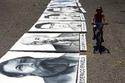 Un niño pasa en su bicicleta junto a varios carteles con imágenes de dirigentes comunistas