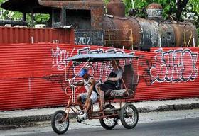 Bicitaxi en La Habana, con una antigua locomotora al fondo