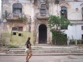 Una mujer camina por un barrio habanero que muestra profundo deterioro