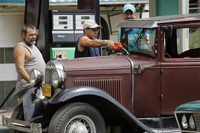 Tres cubanos abastecen de gasolina un auto Ford del año 1932