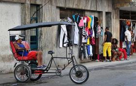 Un bicitaxista espera la llegada de clientes junto a un negocio privado de venta de ropa el lunes 26 de diciembre de 2011 en La Habana