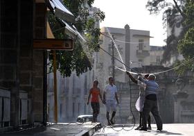 Dos empleados de un hotel limpian los toldos de la entrada, el 24 de diciembre de 2011, en La Habana. EFE