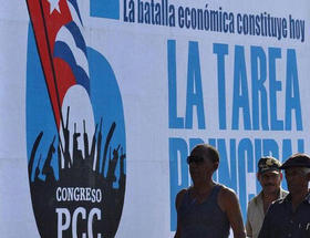 Obreros cubanos frente a un cartel del VI Congreso del PCC