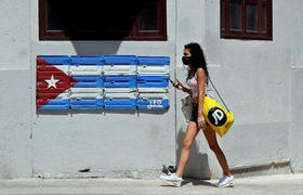 Una mujer camina por una calle con una bandera de Cuba