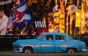 Un taxi pasa frente a un cartel en La Habana en marzo de 2016