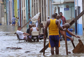 Cubanos juegan dominó en una calle inundada de La Habana