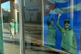 Una mujer camina por una calle de La Habana cerca de un cartel con la imagen de Fidel Castro y su hermano, el presidente cubano Raúl Castro, el jueves 2 de junio de 2011