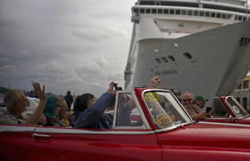 Turistas pasean por la capital cubana en un auto antiguo mientras pasan frente a un crucero anclado en la bahía de La Habana el 17 de enero de 2018
