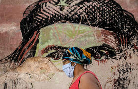 Una mujer con una mascarilla, pasa junto a un mural en ruinas que presenta a Ernesto “Che” Guevara, en La Habana Vieja, Cuba, 19 enero 2021