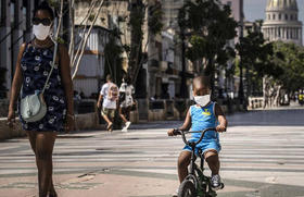 Una mujer acompaña a un niño en bicicleta, ambos con mascarillas protectoras como medida de precaución en medio de la propagación del nuevo coronavirus, en La Habana, Cuba, el viernes 3 de julio de 2020