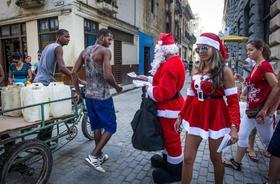Empleados privados vestidos con trajes de Papá Noel reparten folletos que promueven cenas navideñas en restaurantes de La Habana, en esta fotografía de archivo de diciembre de 2014. (Foto de ElComercio.com.)