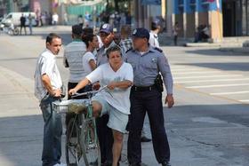 Una mujer cruza junto al cordón policial que solo permite el paso a residentes y trabajadores de la zona donde se encuentra la iglesia pentecostal