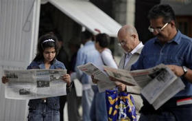Habaneros leen diarios oficiales días después de la 'reestructuración' del gobierno, el 5 de marzo de 2009. (AP)