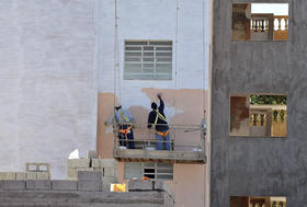 Dos hombres pintan la fachada de un edificio de viviendas, el miércoles 4 de enero en La Habana