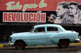 Un «almendrón» pasa junto a un cartel político en Cuba