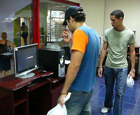 Jóvenes observan una computadora en un centro comercial de La Habana. (CE)