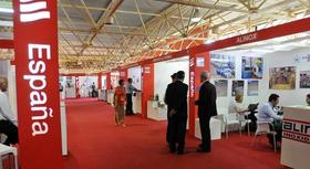 Varias personas caminan frente a mostradores de diferentes empresas españolas que participan en la XXIX Feria Internacional de La Habana