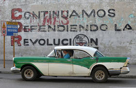 Un antiguo automóvil estadounidense pasa delante de un muro con la leyenda «Continuamos defendiendo la revolución», el 20 de marzo de 2018 en La Habana