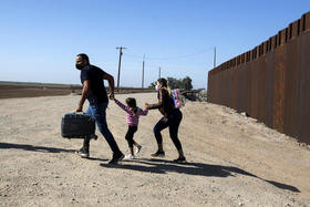 Una familia de migrantes cubanos corren tras cruzar el muro que separa México de Estados Unidos para entregarse a las autoridades en Yuma, Arizona