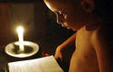 Niño cubano estudia a la luz de una vela durante un apagón