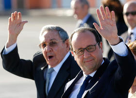 El presidente francés François Hollande y el gobernante cubano Raul Castro saludan a los reporteros durante la ceremonia de despedida a Hollande en el Aeropuerto Internacional José Martí en La Habana, el 12 de mayo de 2015