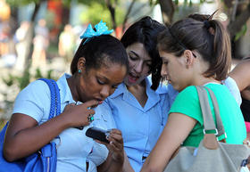 Estudiantes cubanas utilizando un teléfono celular
