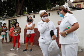 Dos enfermeras esperan el ómnibus el 19 de abril de 2021 en La Habana, Cuba