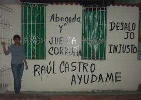 Yamilé Bargés Hurtado junto a la pared de su vivienda en que pintó letreros denunciando de desahucio