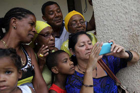 Un grupo de cubanos observa la llegada del presidente de EEUU, Barack Obama, a Cuba a través de la señal de televisión captada por un teléfono móvil, el domingo 20 de marzo de 2016 en La Habana