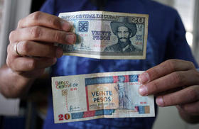 Un hombre muestra un billete de 20 pesos cubanos y otro de 20 pesos convertibles
