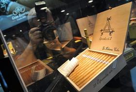 Un hombre toma una foto a una caja de puros, mientras participa en el XIII Festival del Habano que se inauguró en La Habana