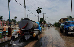 Un conductor se refresca mientras llena el tanque de un camión cisterna en La Habana, Cuba
