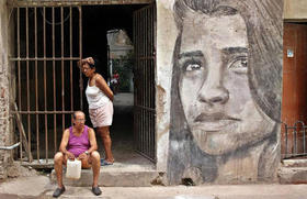 Dos personas permanecen en la puerta de una vivienda, junto a un mural, el viernes 15 de abril de 2016, en La Habana