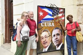 Turistas en La Habana junto a cartel sobre la visita de Barack Obama a Cuba