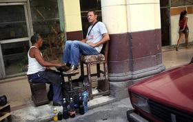 Un lustrador de calzado atiende un cliente en La Habana