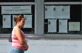 Una mujer camina junto a carteles alusivos a las elecciones de los delegados a las asambleas (foto: Martínoticias)